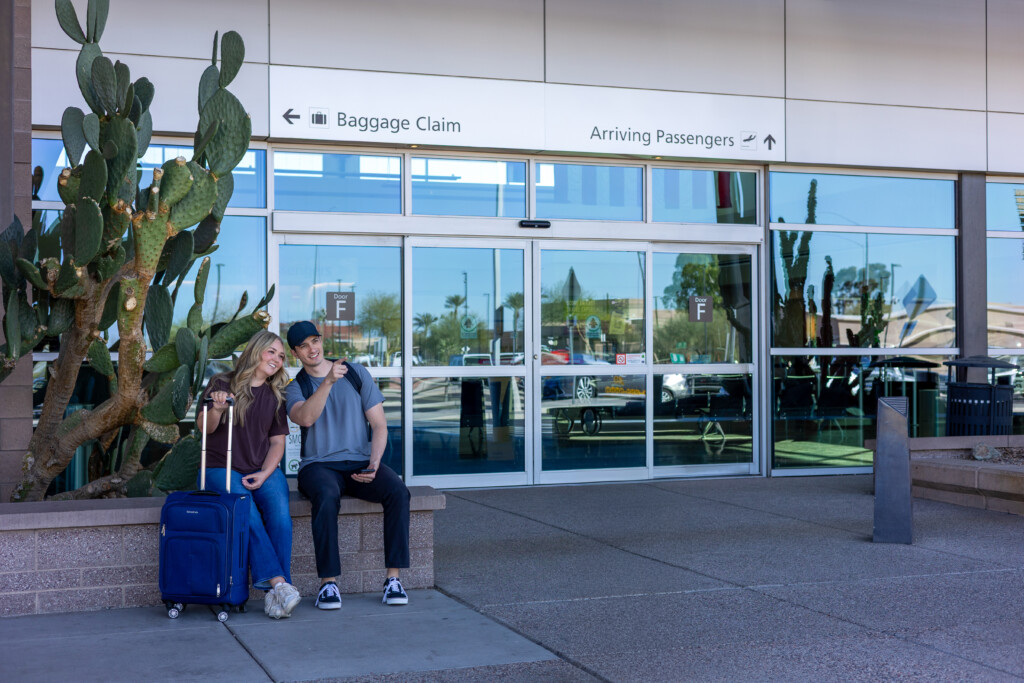 Couple waiting with luggage outside the arrivals entrance