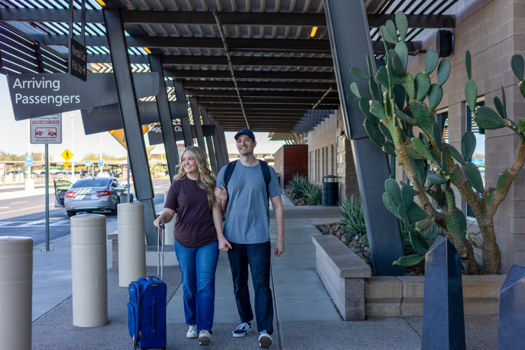 Couple with luggage walking to the arriving-passenger pickup area