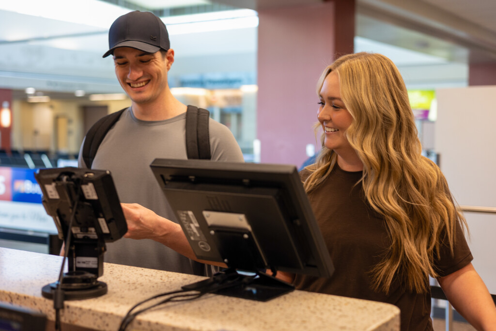 Traveler at a check-in kiosk being helped by an airline agent