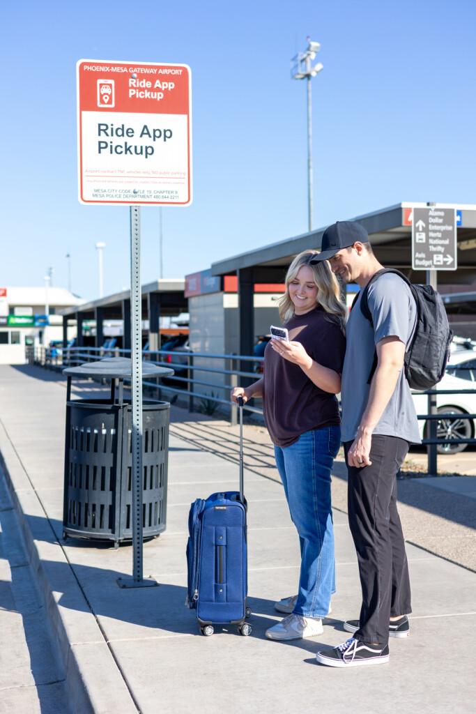 Travelers waiting beneath the ride app pickup sign
