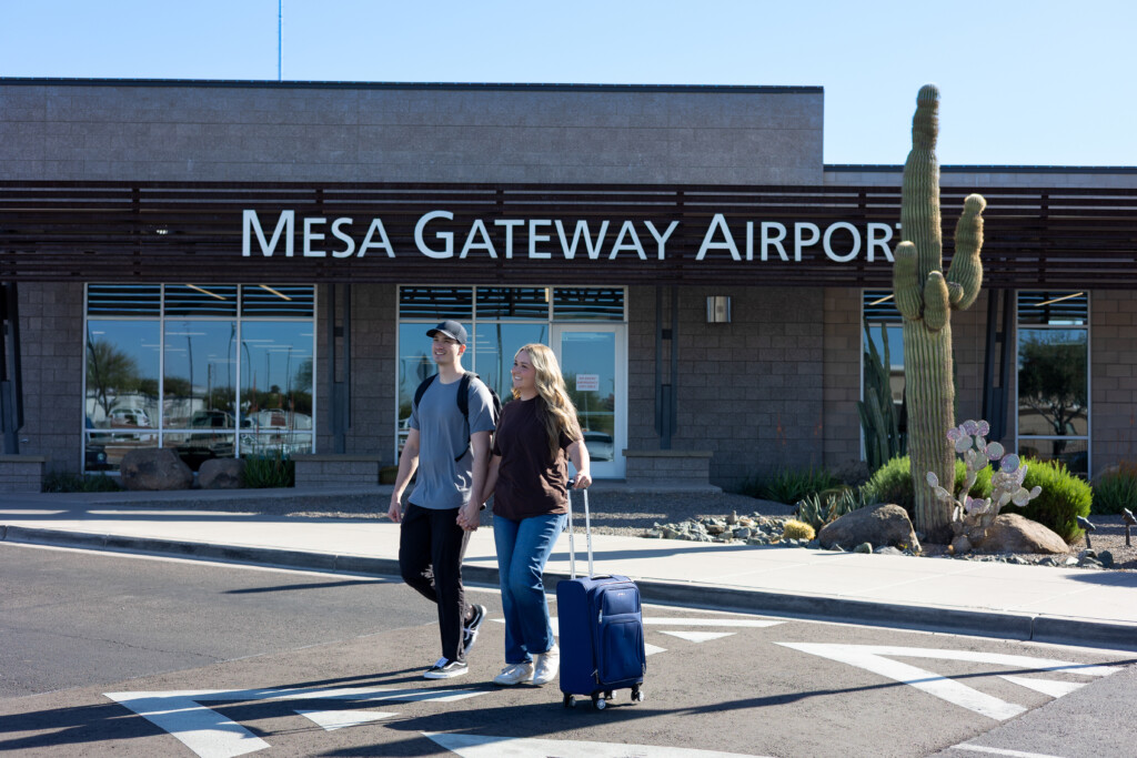 Couple with rolling luggage walking toward the terminal entrance