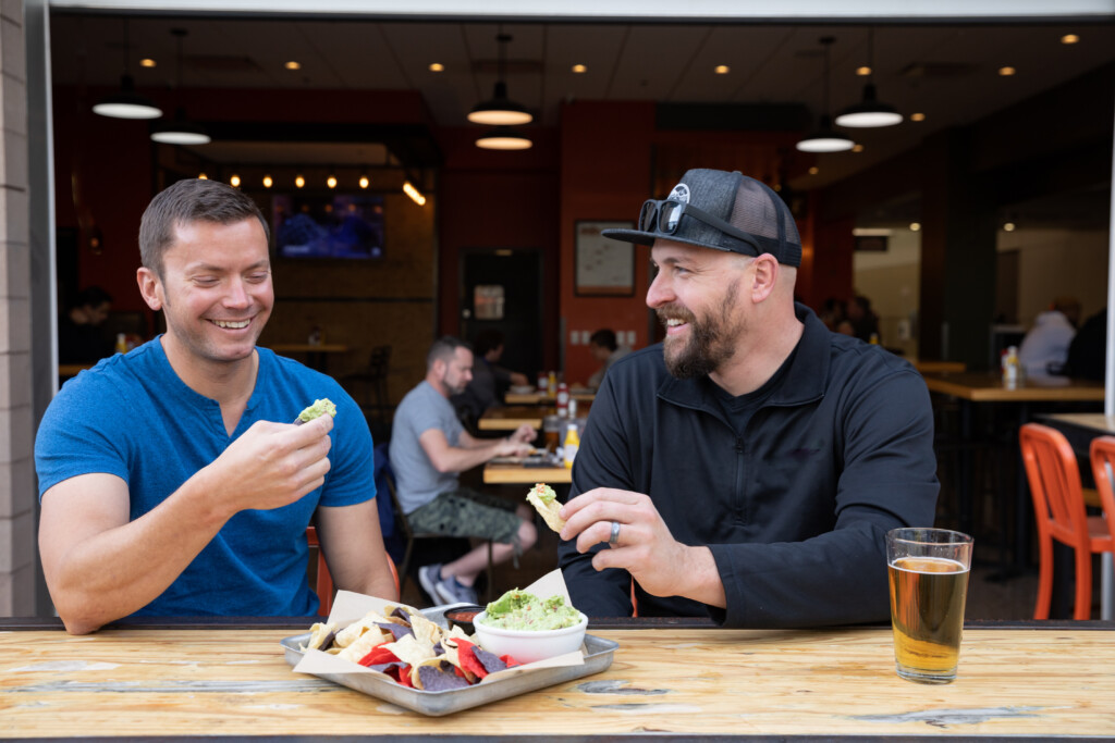 Two men enjoying burgers and beers at a terminal restaurant