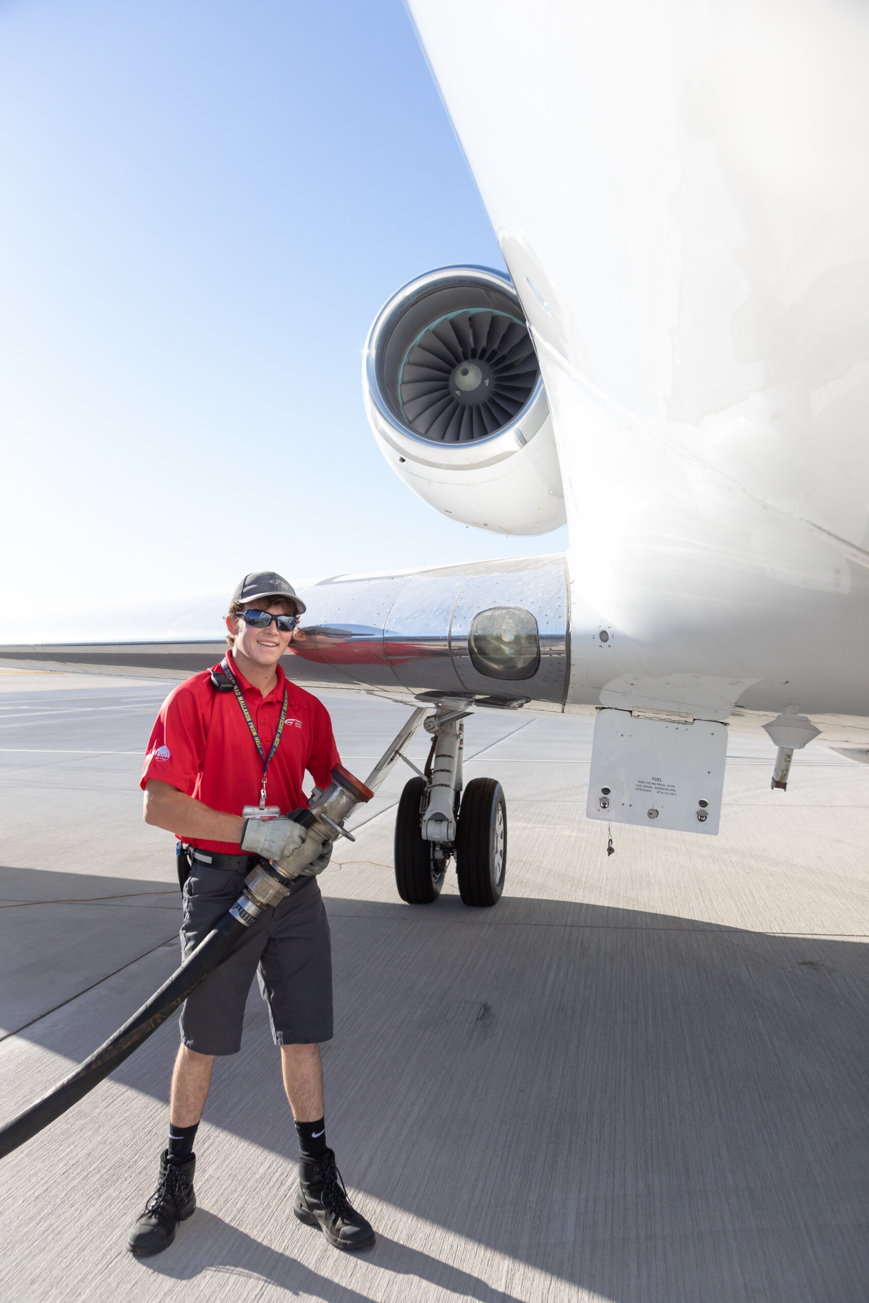 Line technician holding a fuel hose beneath an aircraft wing