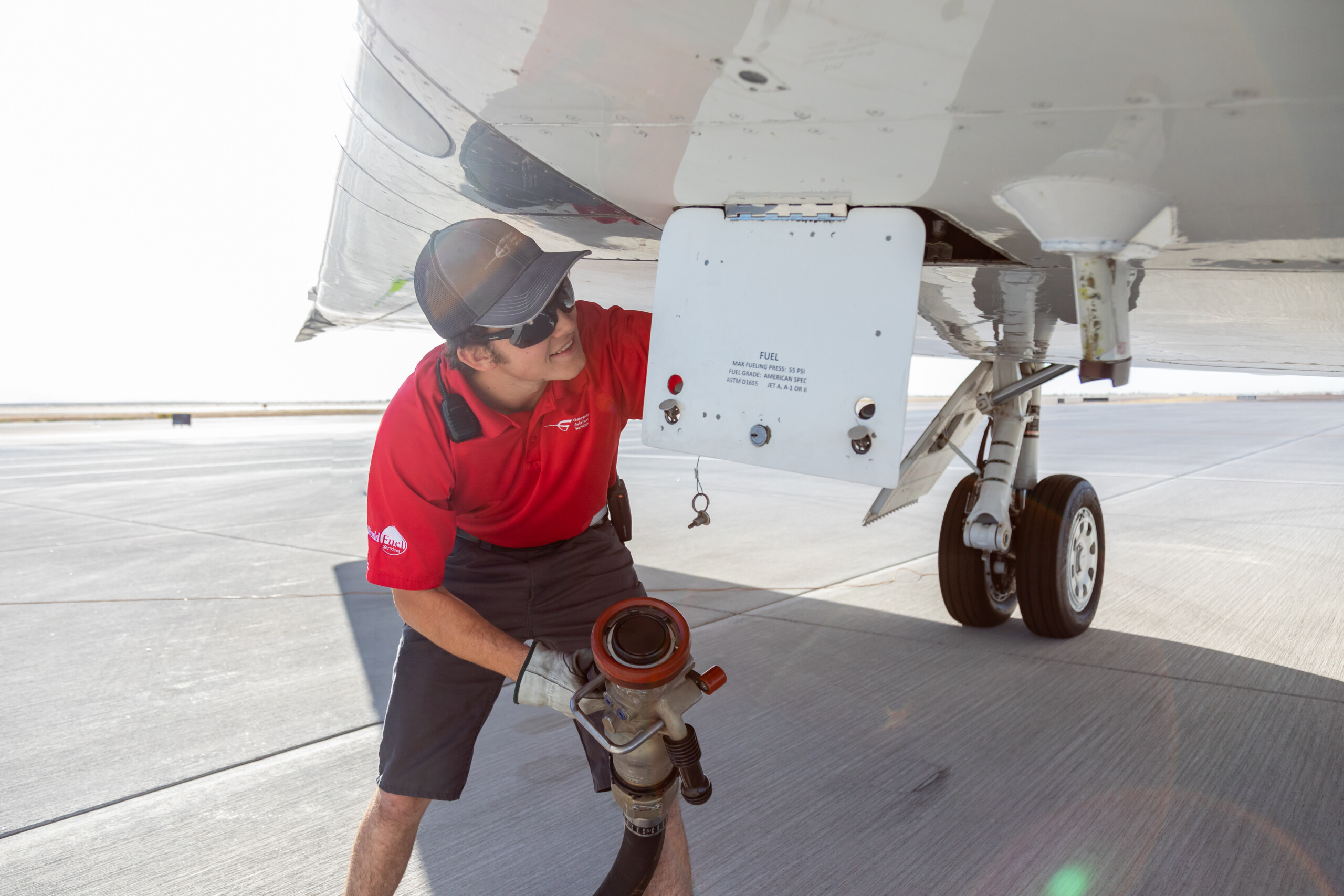 Technician connecting a fuel line under an aircraft