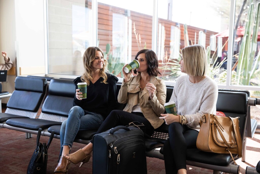 Three friends chatting over coffee in the gate seating area