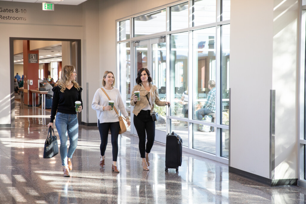 Three travelers with luggage walking through the terminal