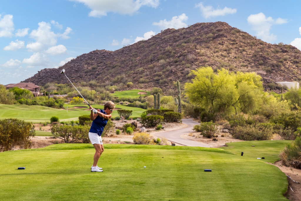 Golfer teeing off with a desert mountain backdrop