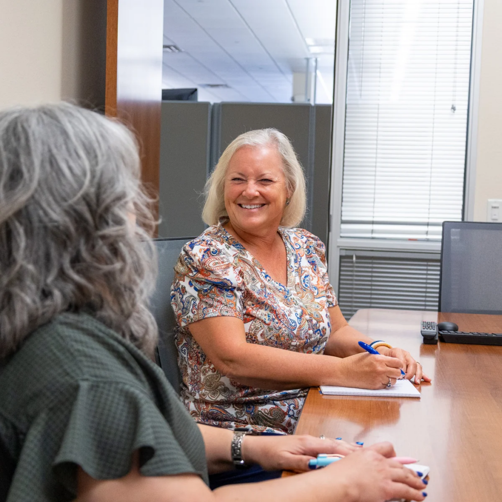 Two colleagues talking across a desk in an airport office
