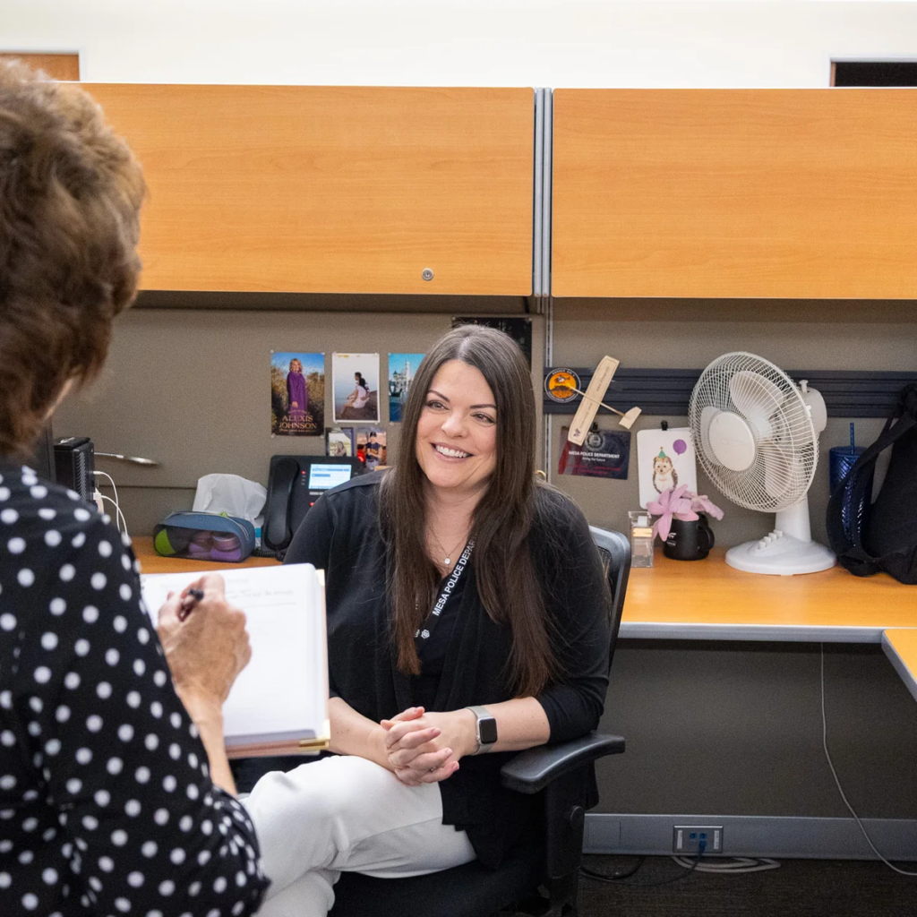 Employee smiling while taking notes at her workstation