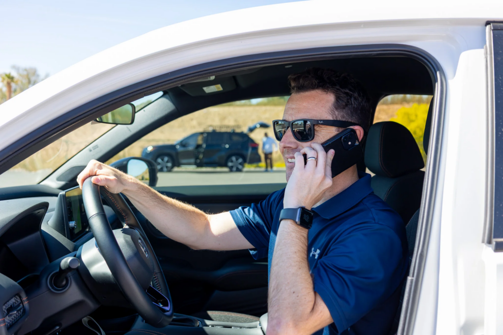 Driver waiting in his car in the Cell Phone Lot while talking on the phone