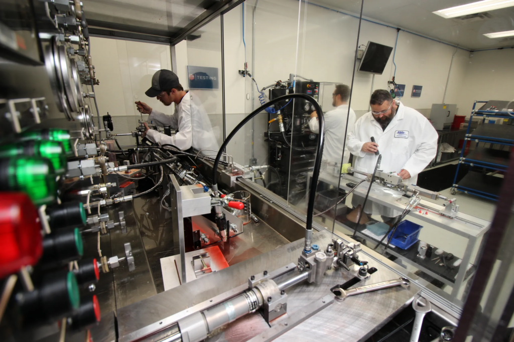 Technicians in lab coats working on aircraft equipment in a workshop