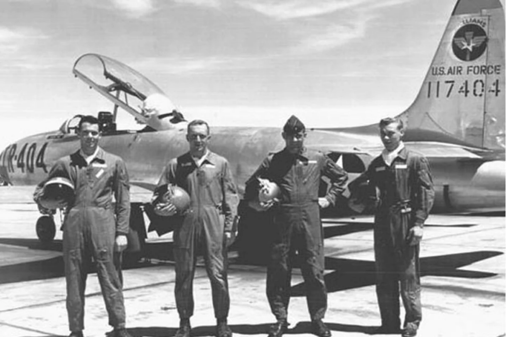 Black-and-white photo of four pilots beside a U.S. Air Force training jet at Williams Air Force Base