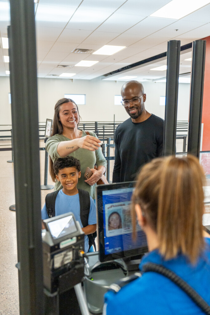 Family at the security checkpoint document-check station with a TSA officer