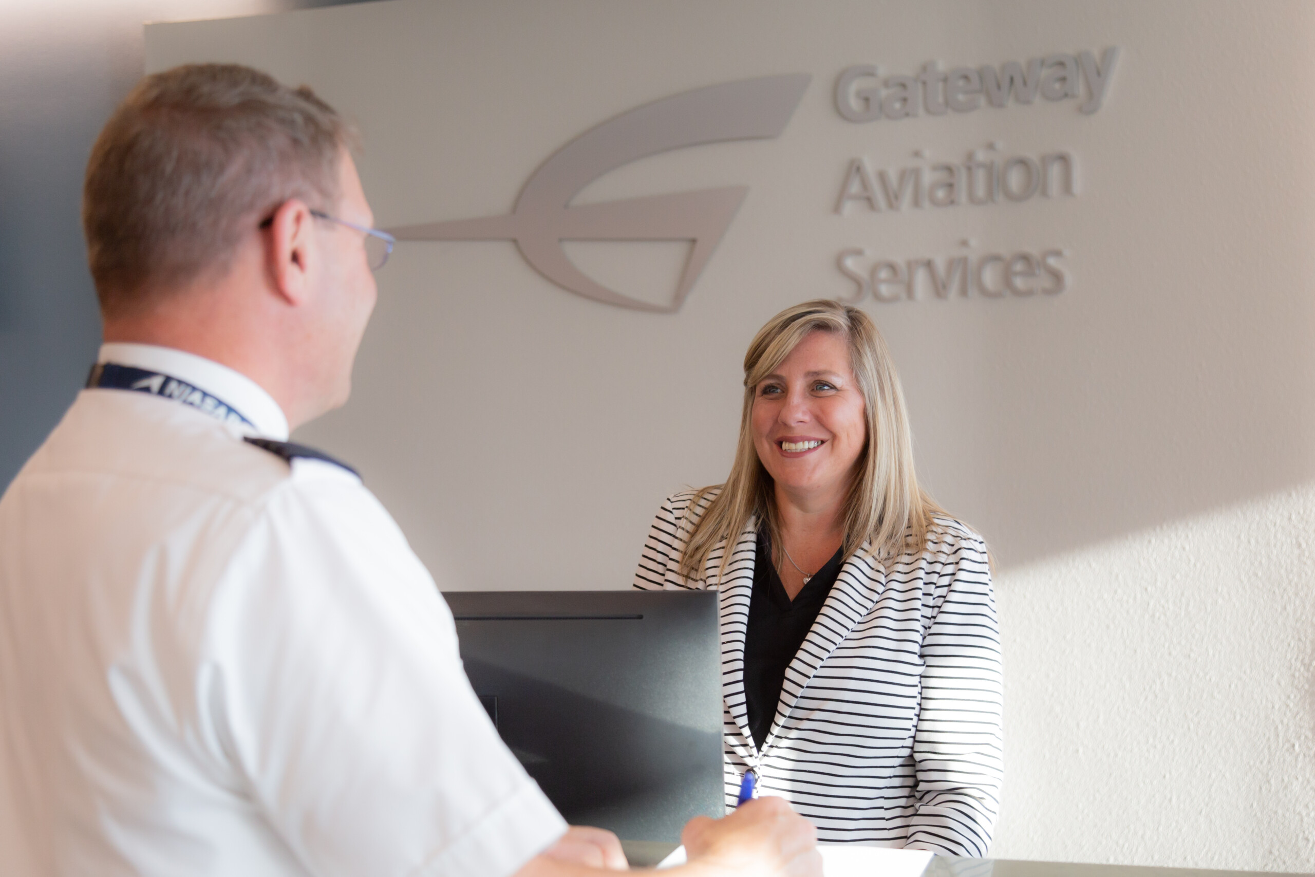 Customer service agent greeting a client at the Gateway Aviation Services desk