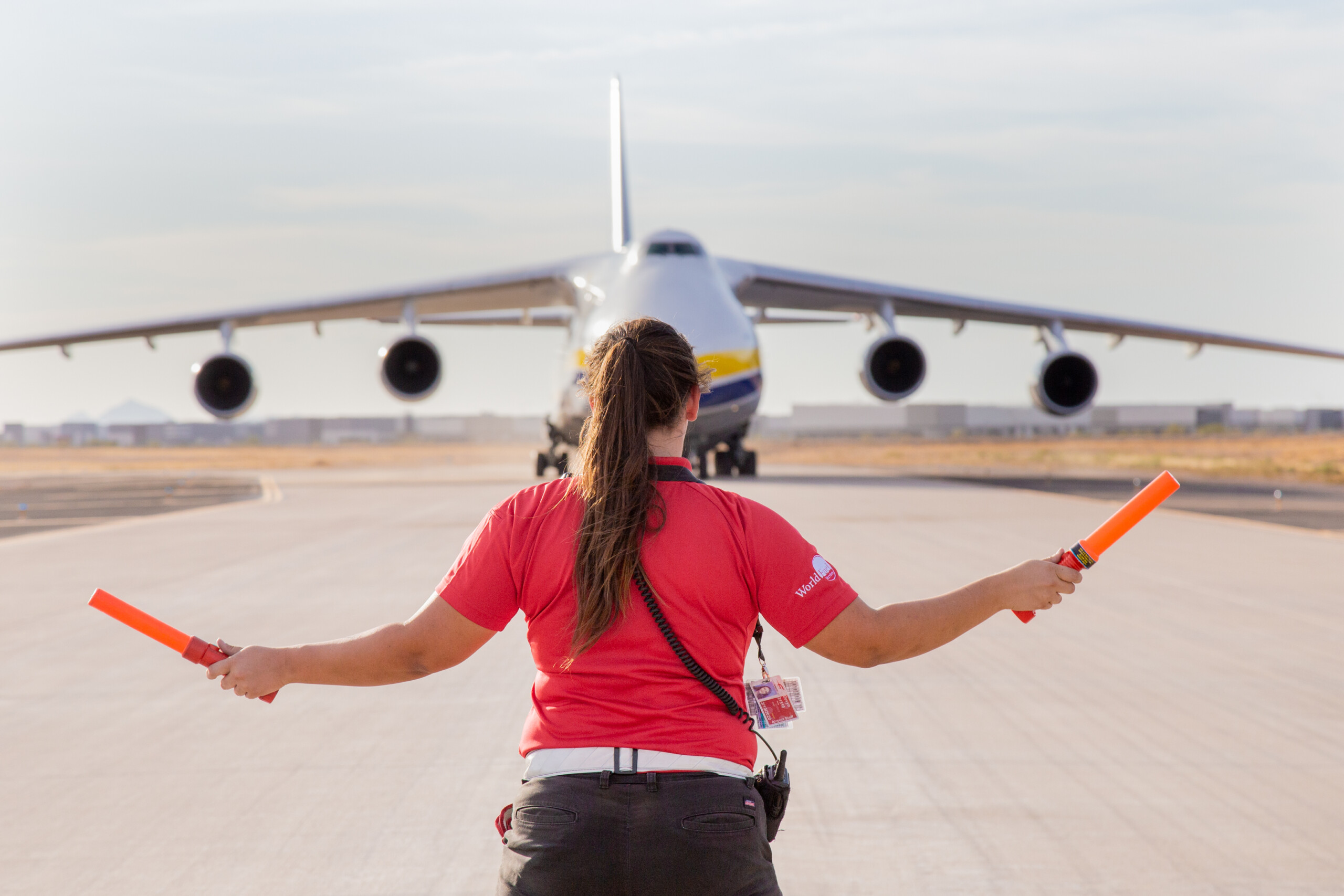 Marshaller guiding a large cargo aircraft with wands