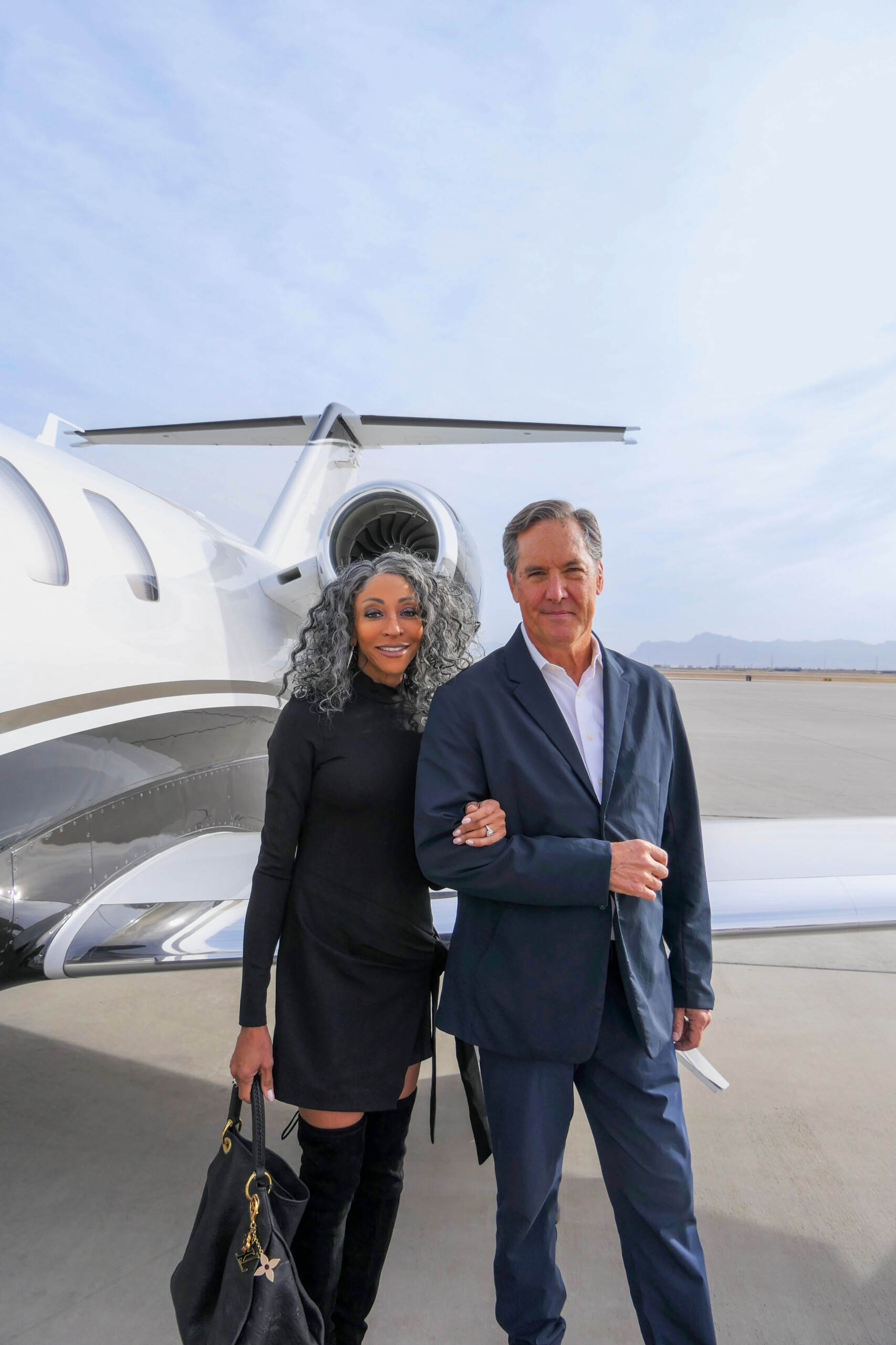 Two passengers posing in front of a private jet