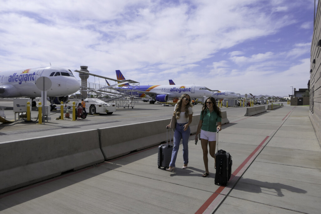 Travelers walking across the ramp from an Allegiant aircraft