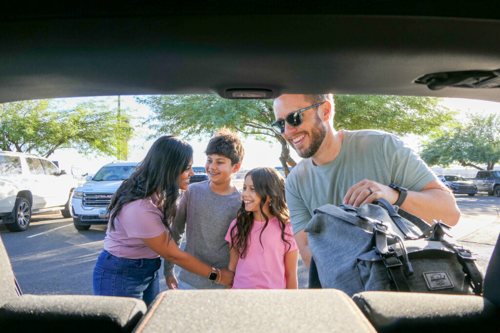 Family unloading luggage from a vehicle at the airport