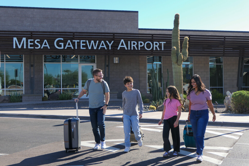 Family with luggage walking toward the terminal entrance