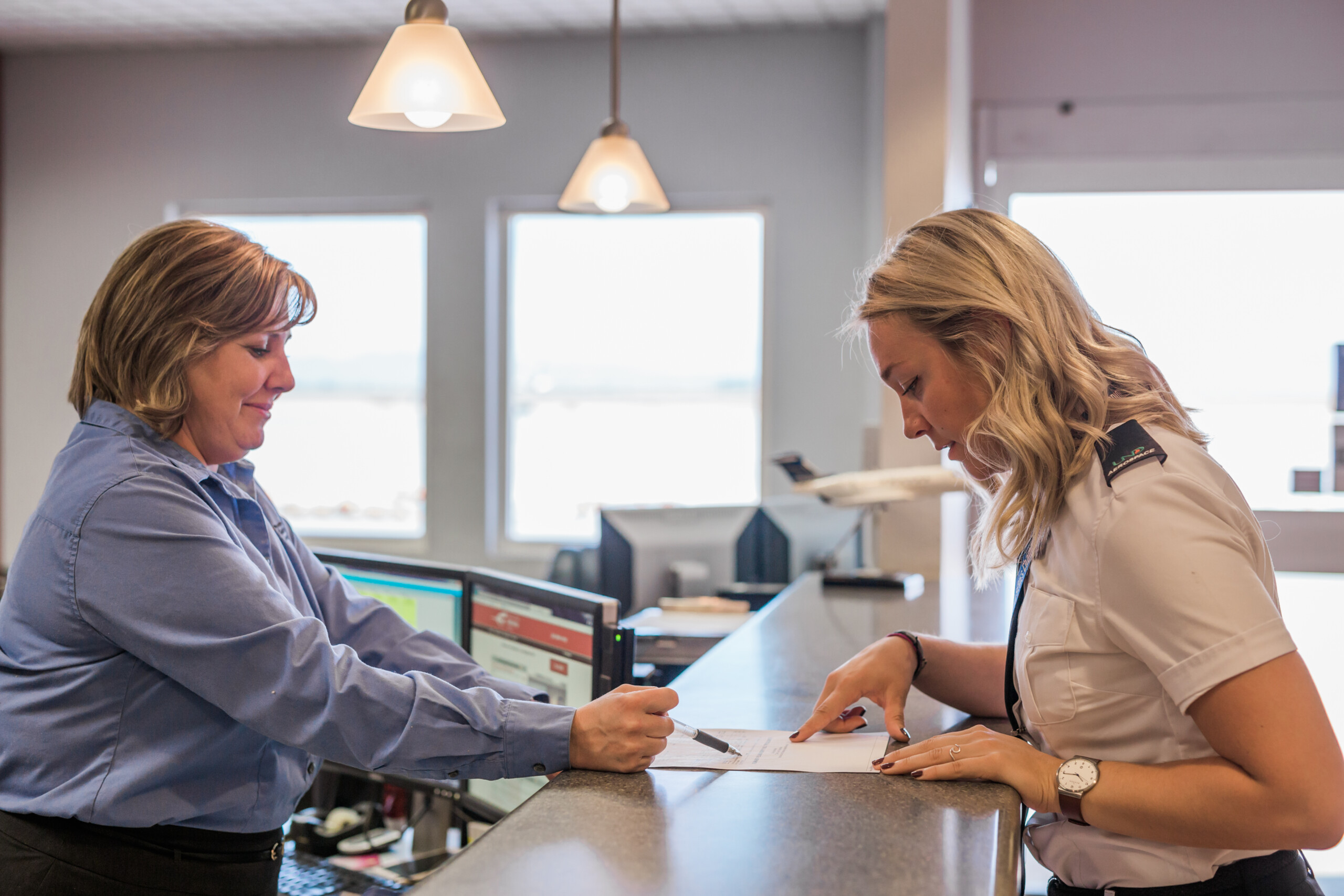 Two staff members reviewing paperwork at the FBO front desk