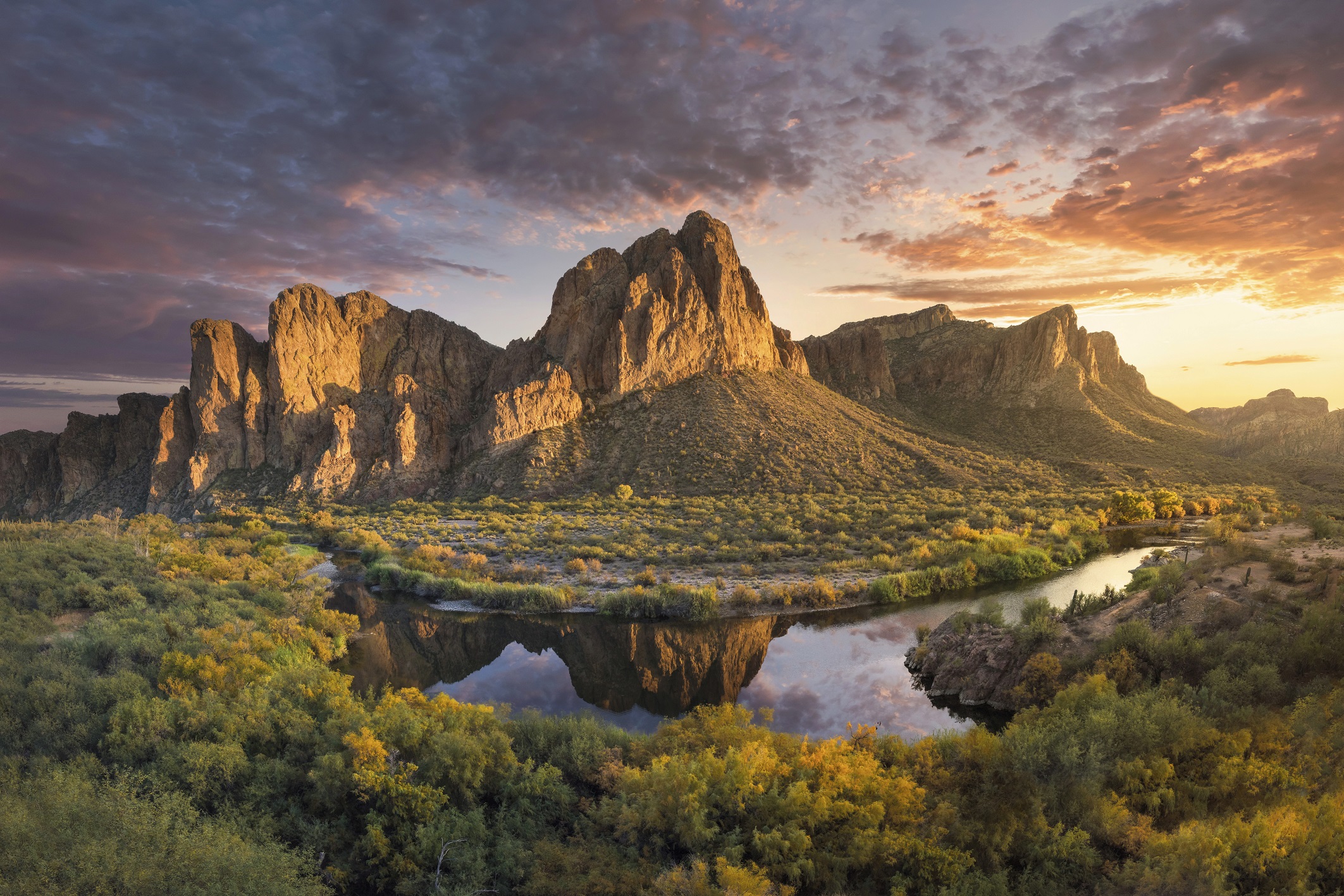 Superstition Mountains reflected in still water at sunset