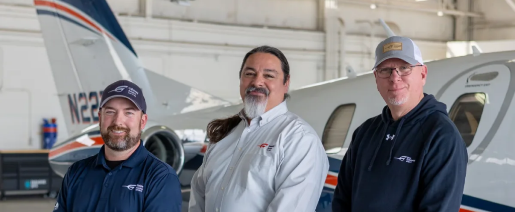 Three Gateway Aviation Services team members standing in a hangar in front of a private jet