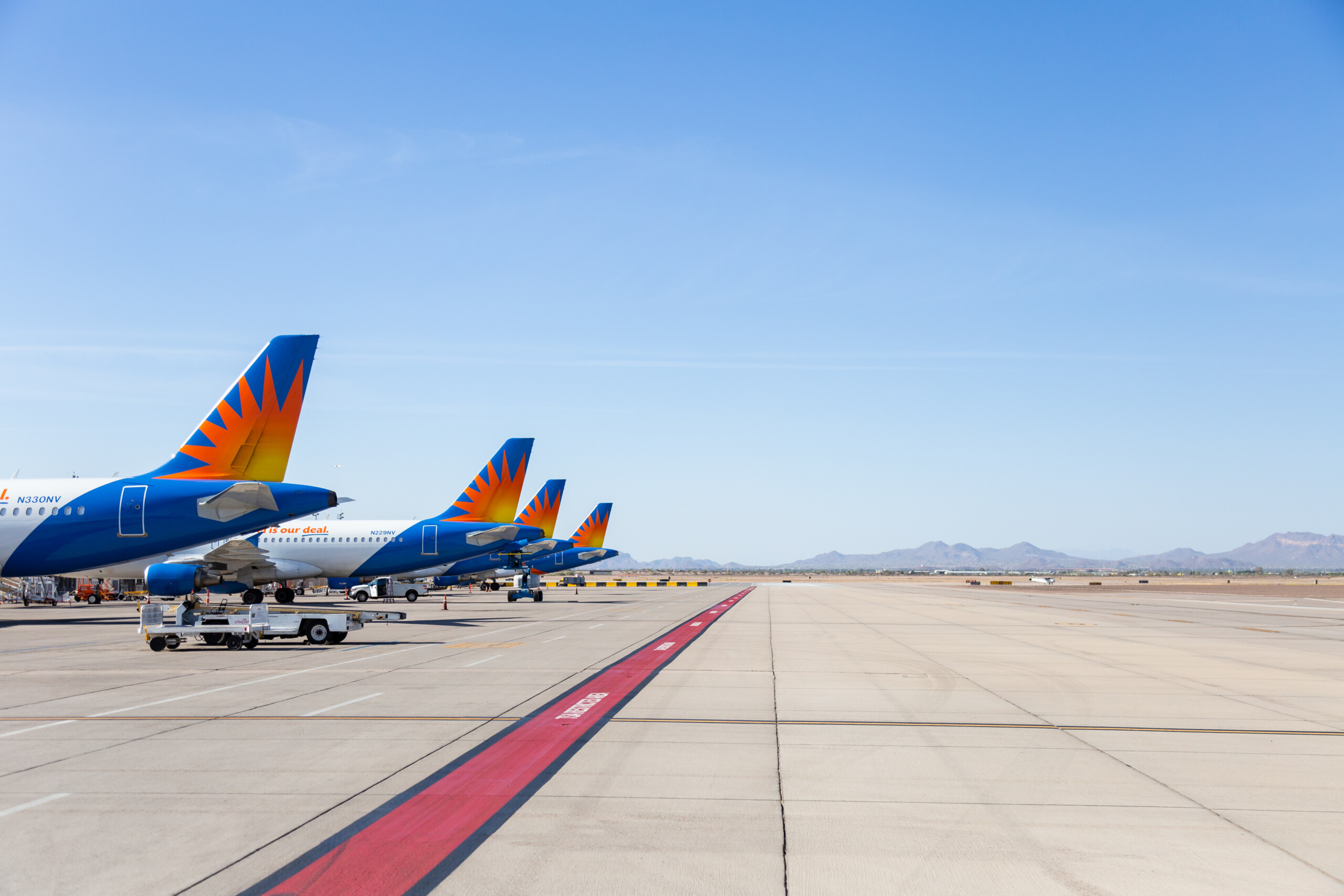 Allegiant aircraft lined up at the gates along the ramp