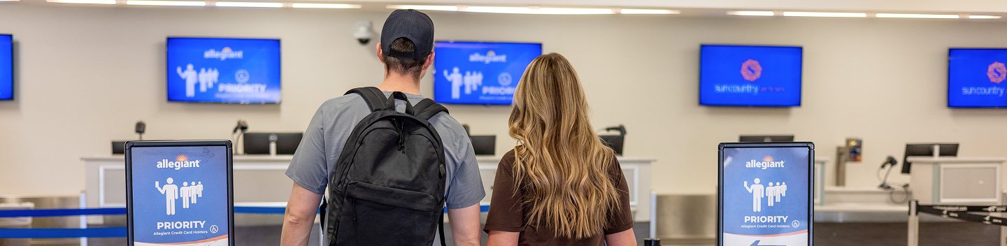 Travelers at the airline ticket counters beneath flight information screens