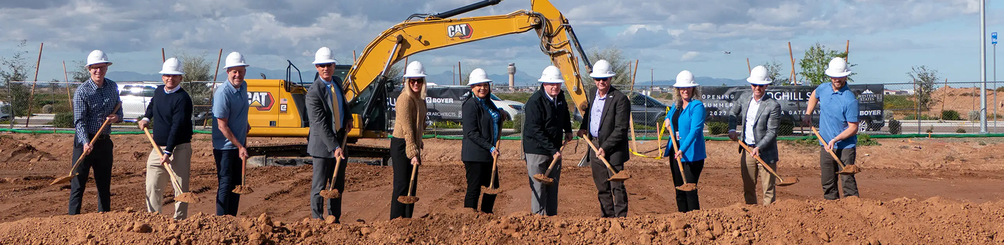 Officials in hard hats breaking ground with shovels at a construction site
