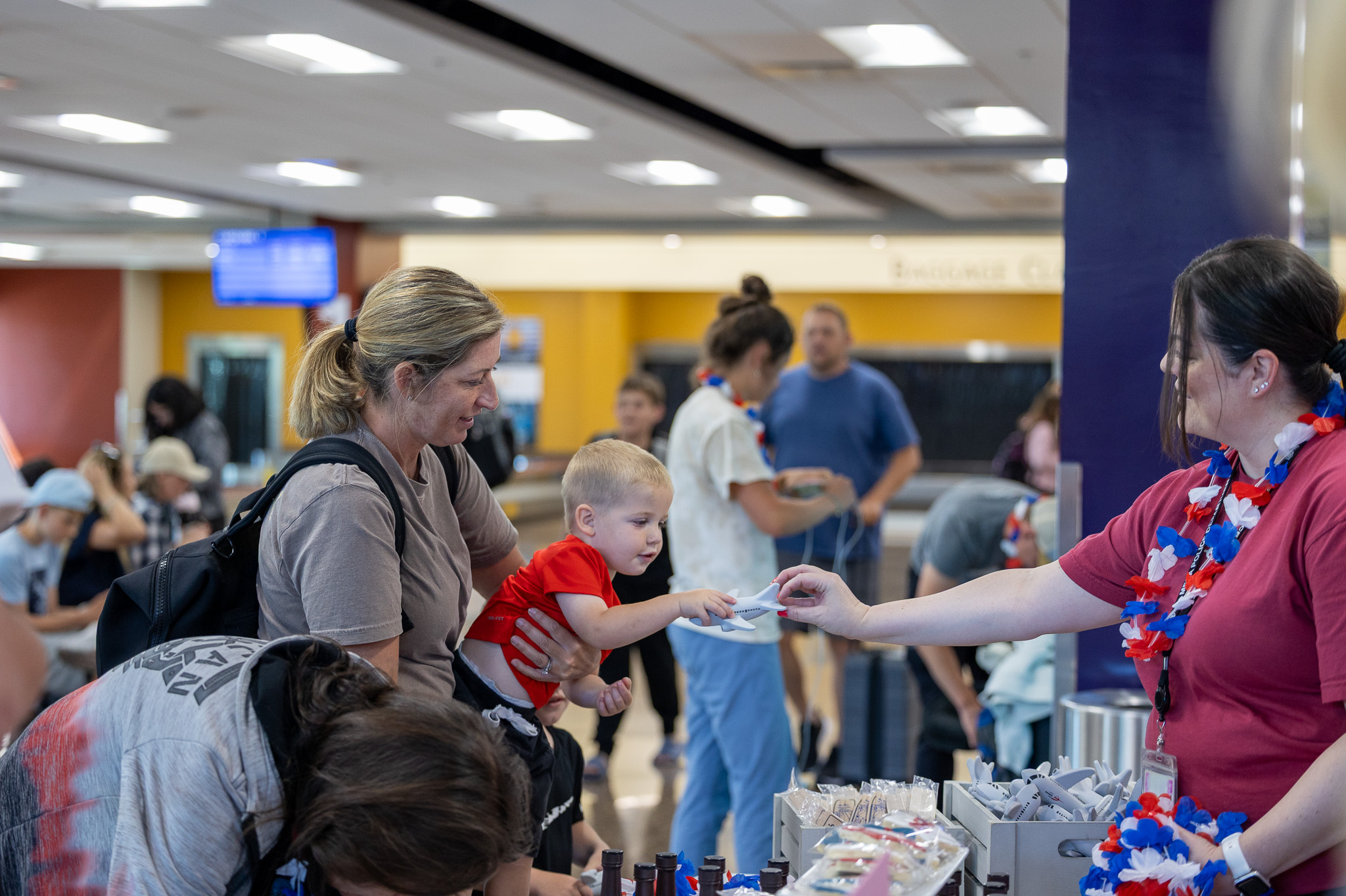 Volunteer handing an item to a child and family at an airport event